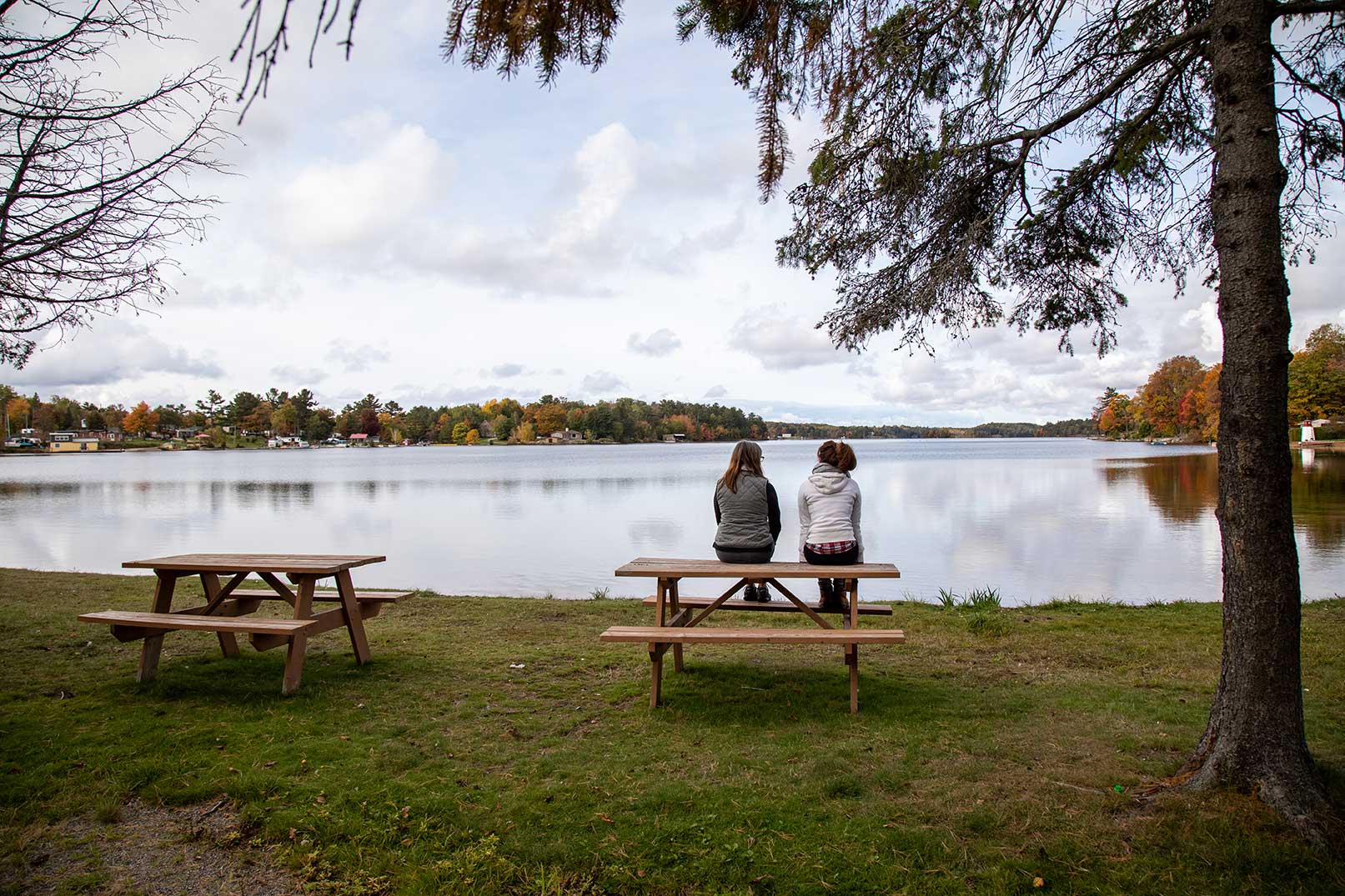 2 people sitting on picinc table overlooking a lake