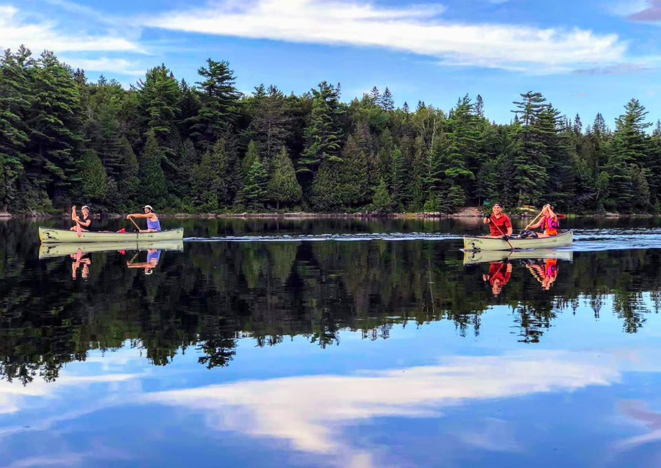 Two canoes on water with people