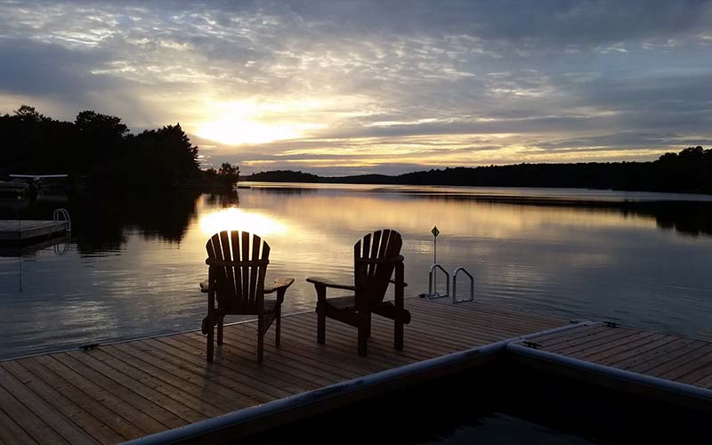 adirondack chairs on dock at sunset