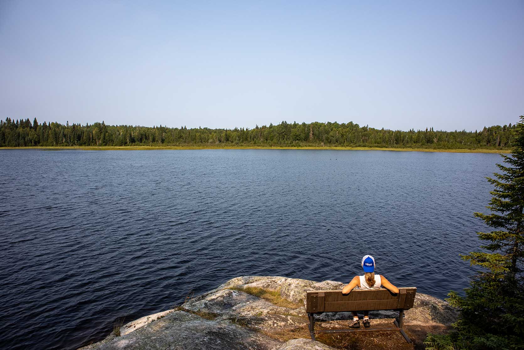 person sitting on bench over looking lake