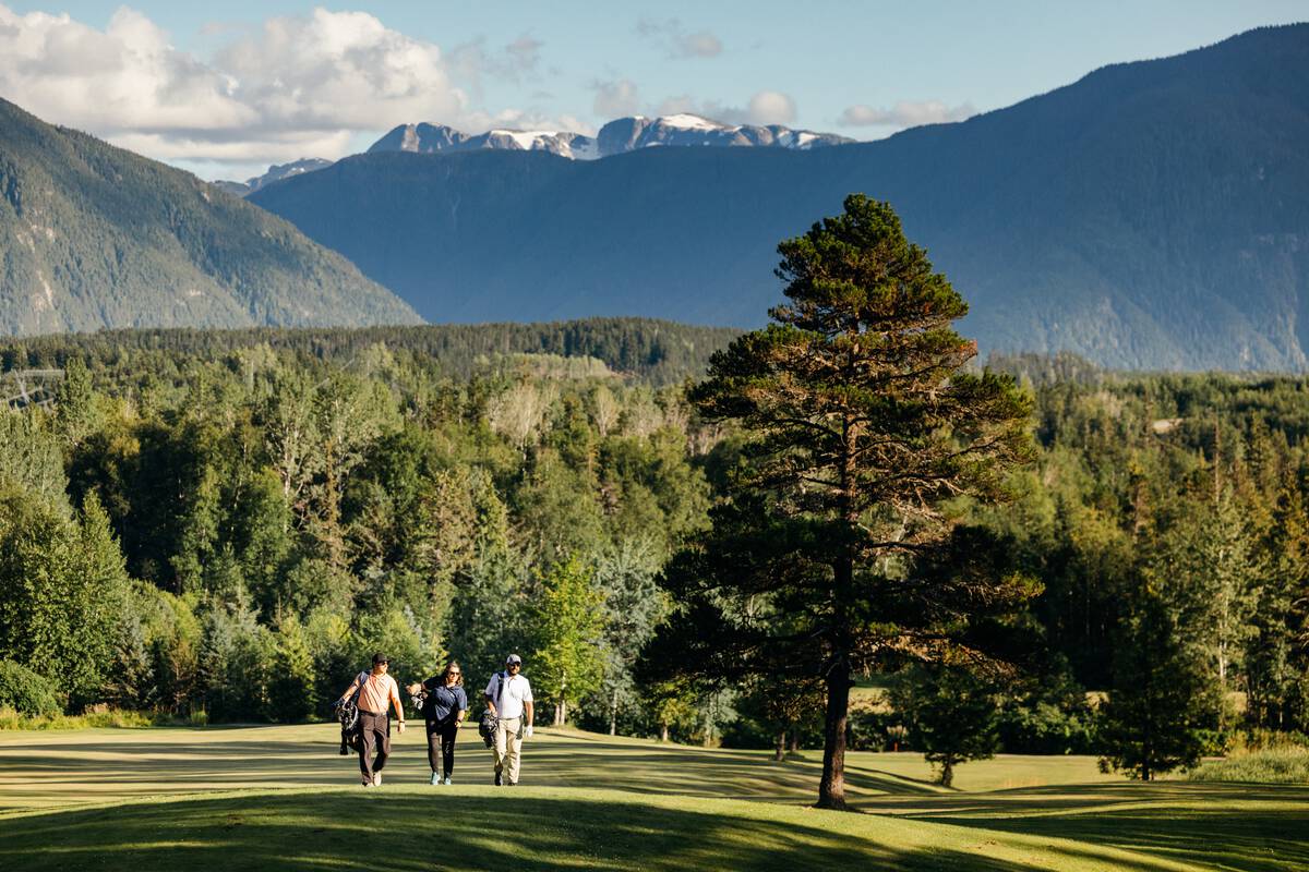 3 golfers walking the course with mountains in background