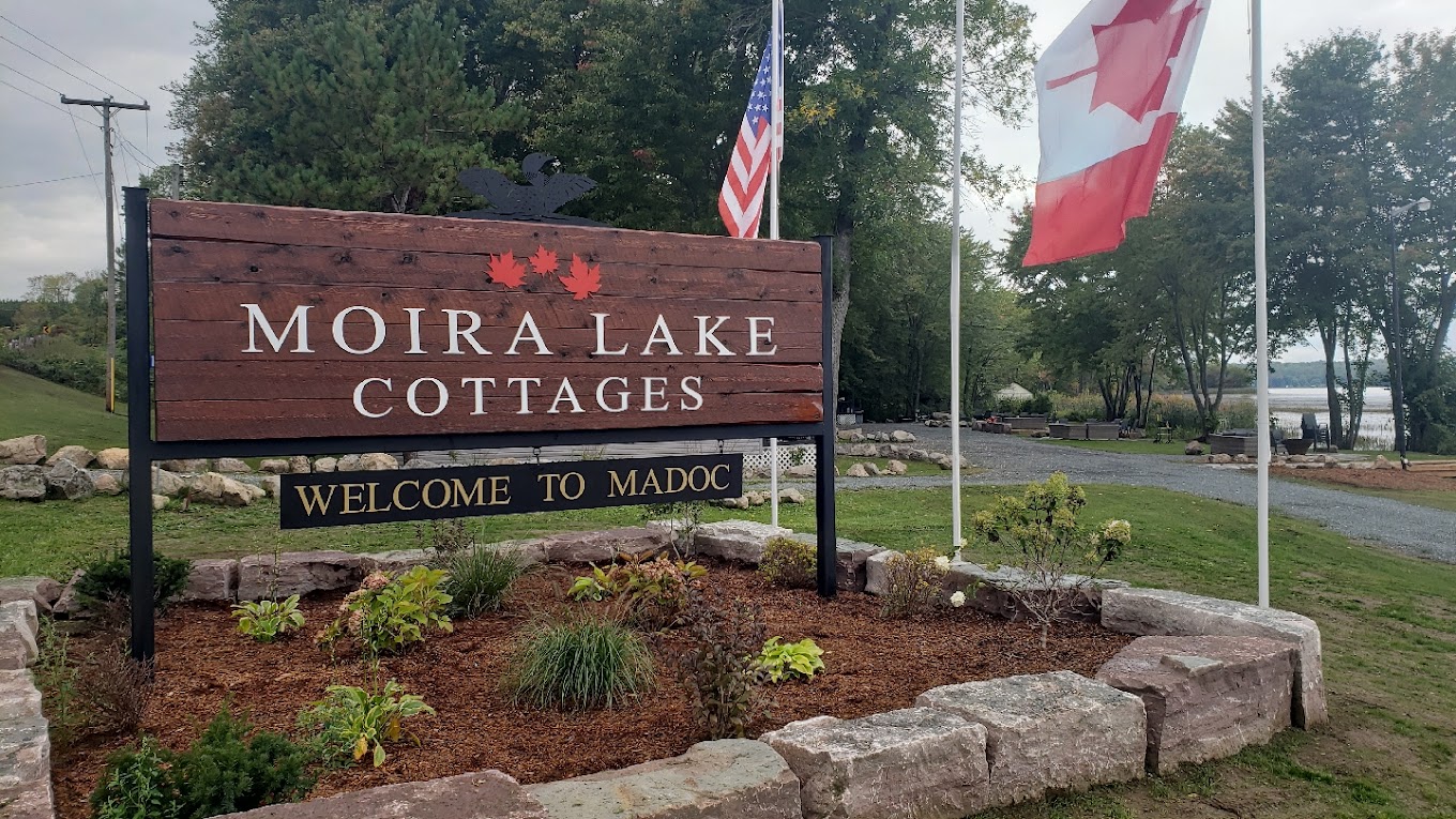 Wooden sign that states "Moira Lake Cottages"