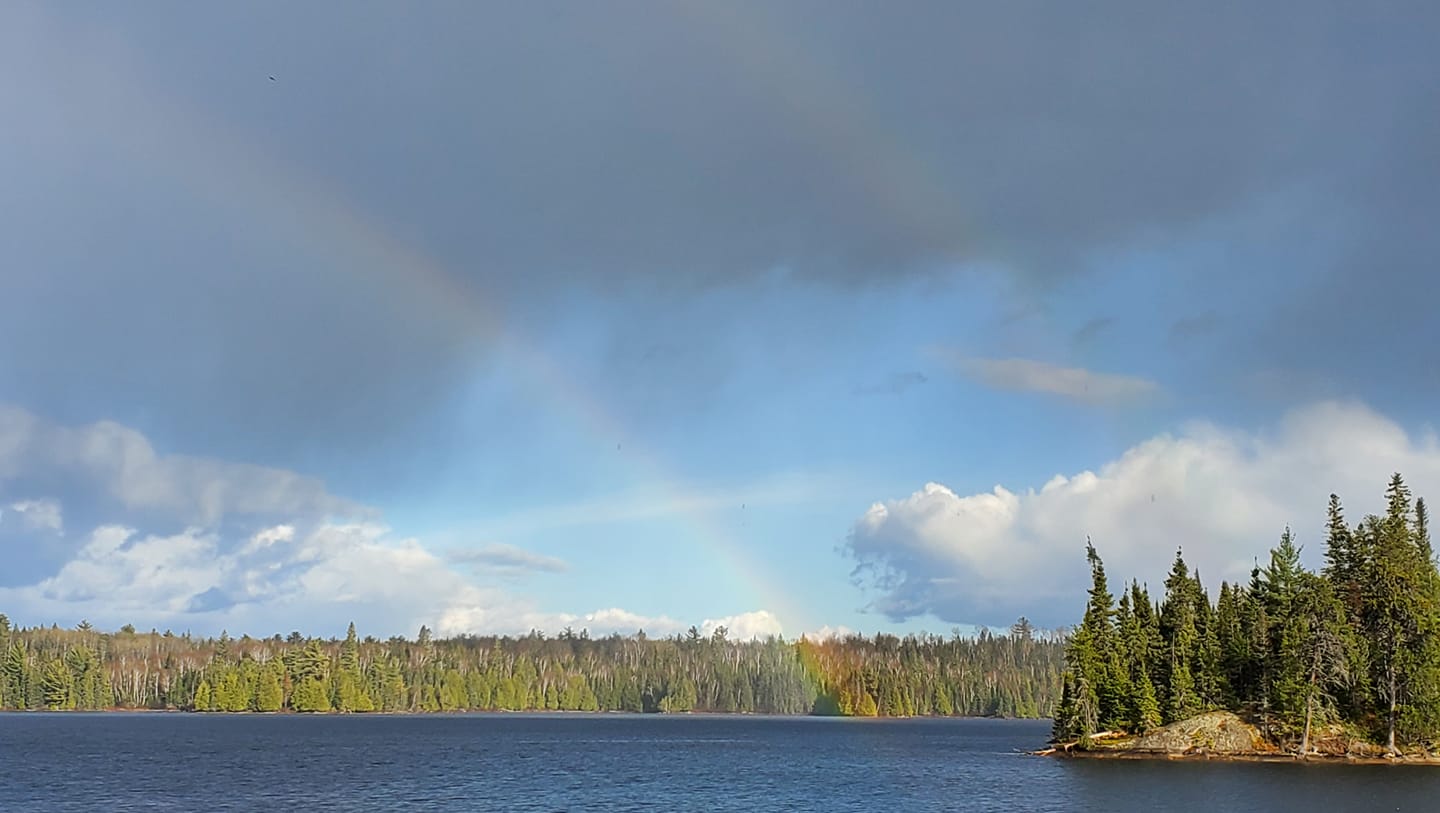 View of lake from shoreline with a rainbow