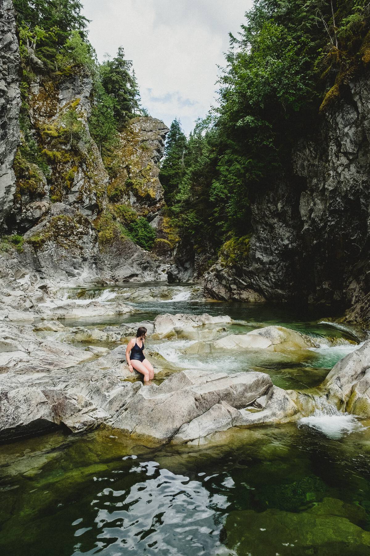 swimmer on rocks in river within a canyon