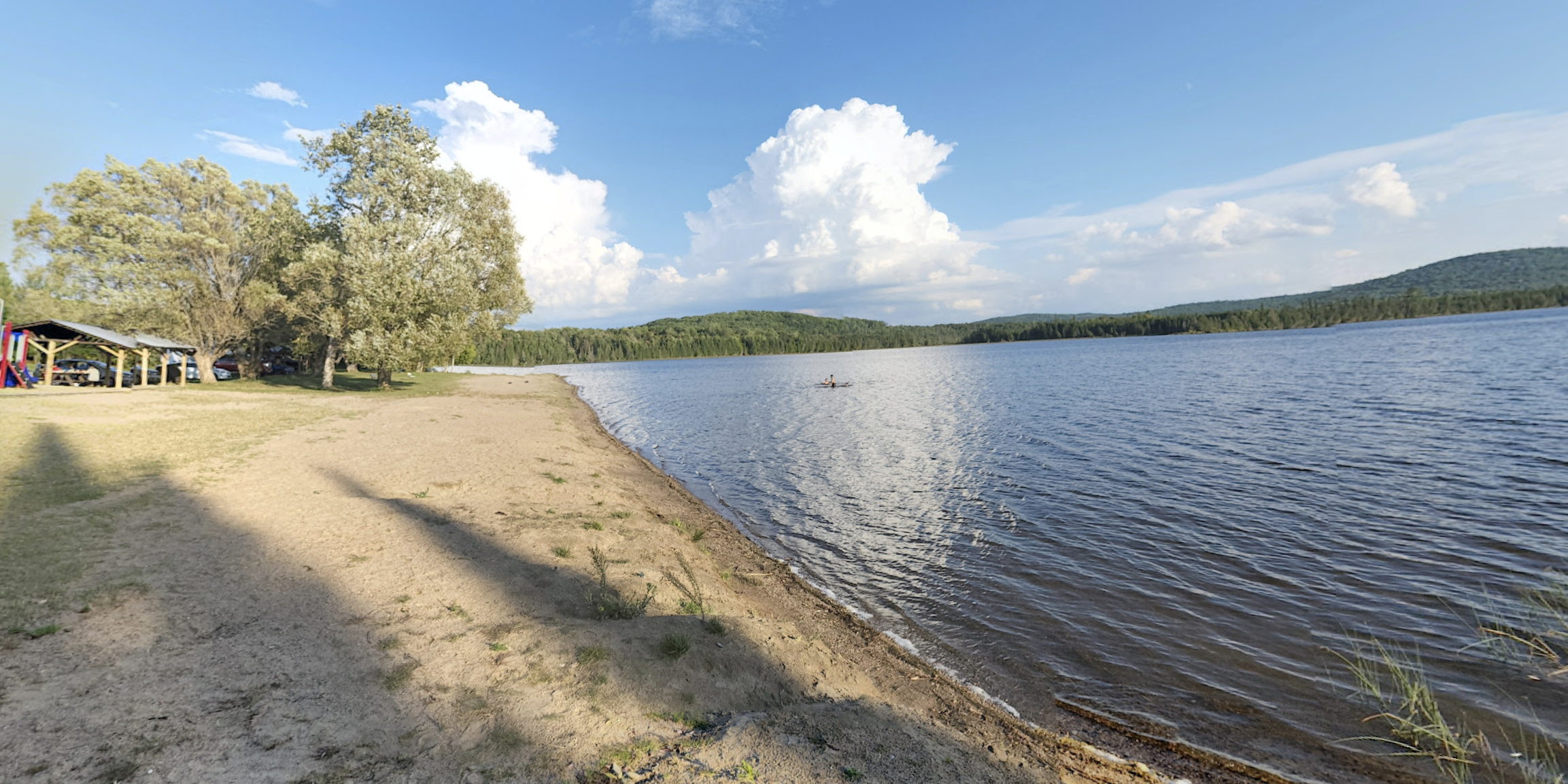 beach and calm lake on blue sky day