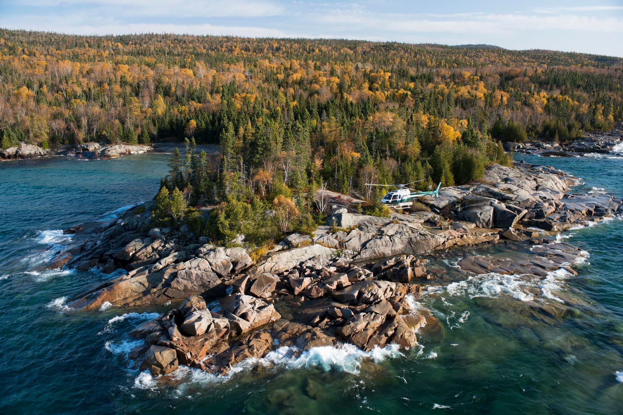 Helicopter flying past rock and lake