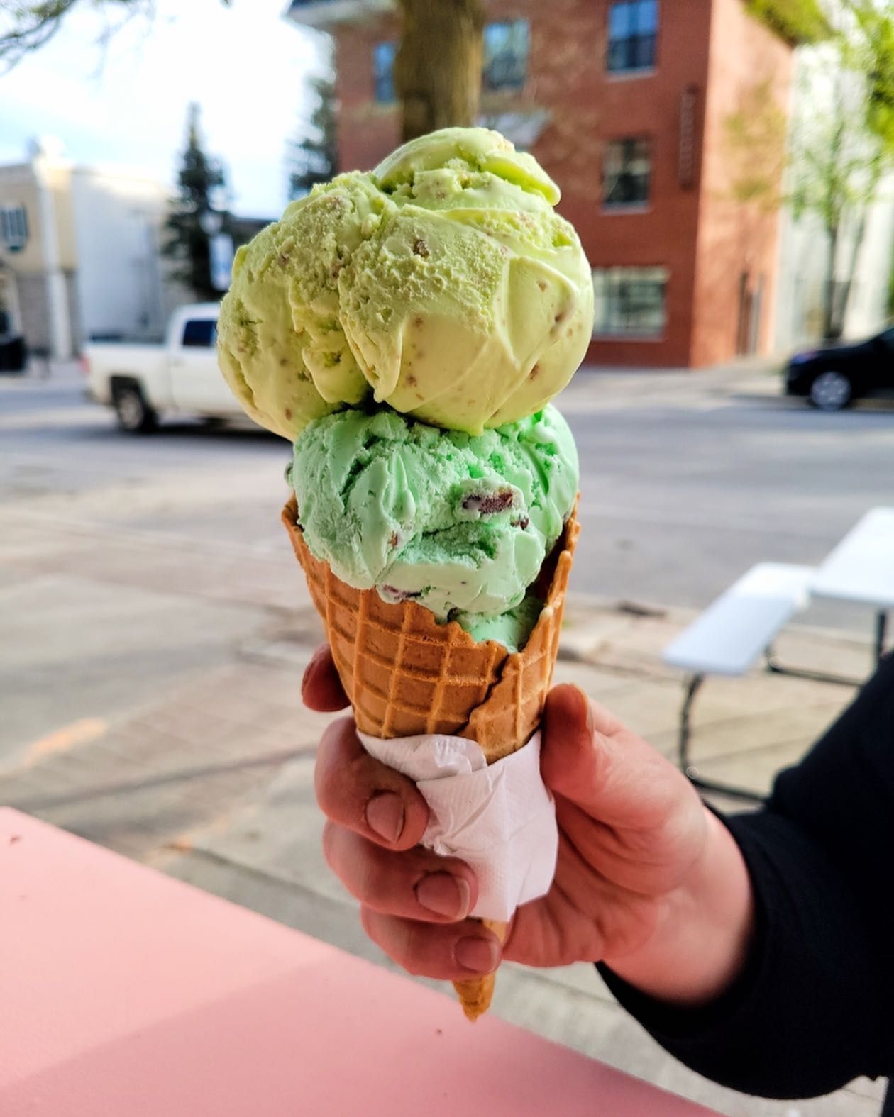 a person holding an ice cream cone with two scoops