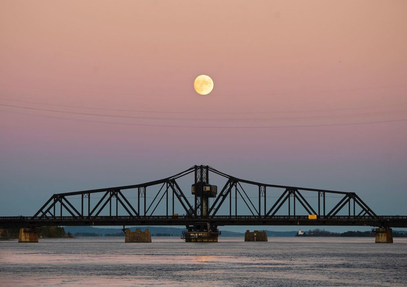 the swing bridge with the moon above it