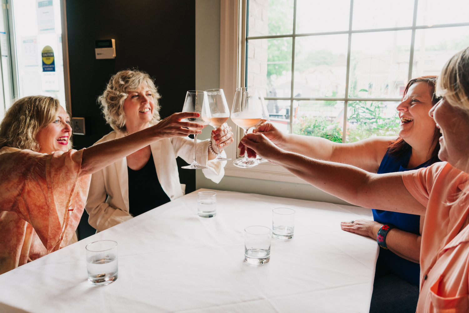 a group of women cheering glasses at a table