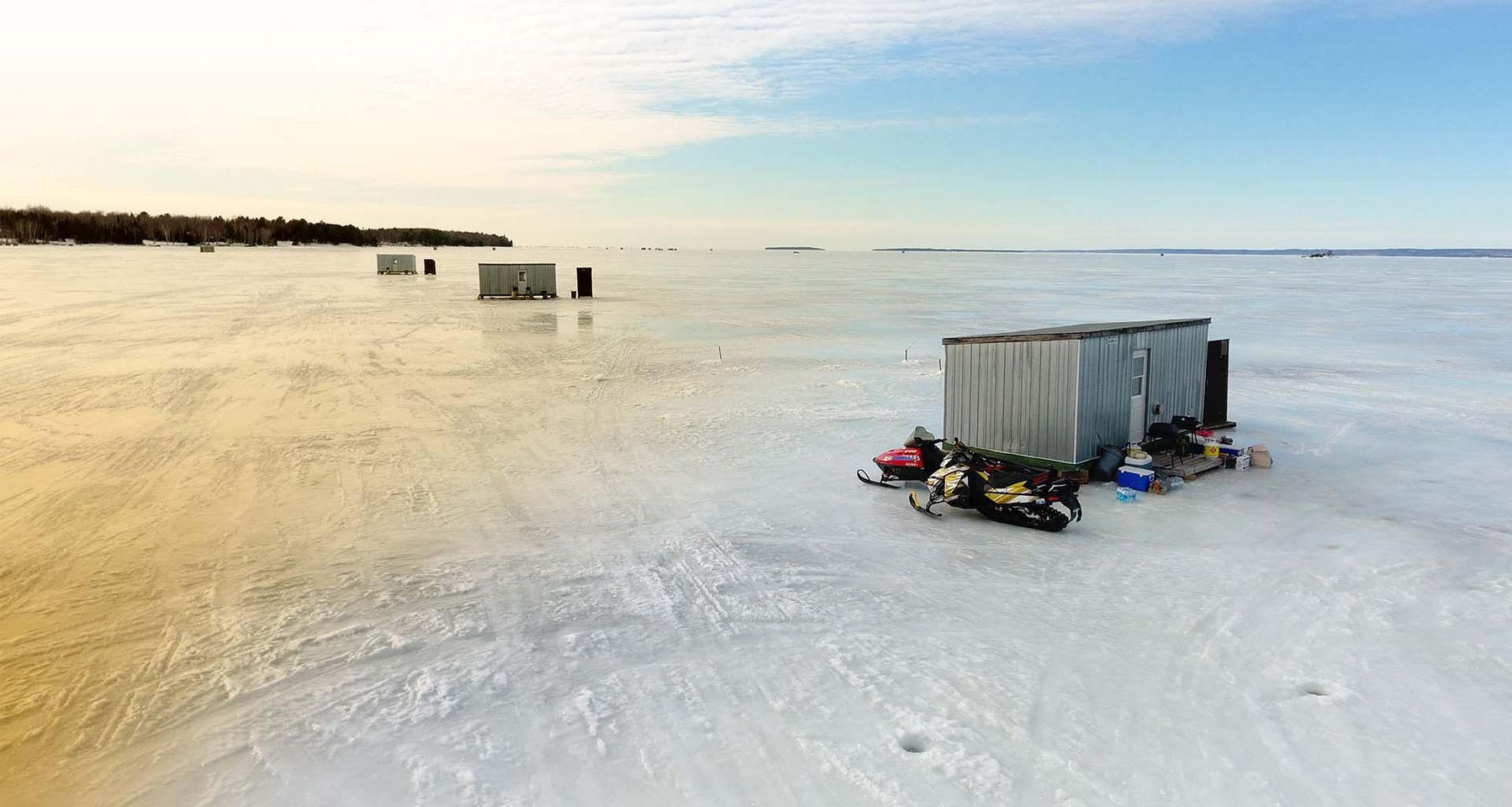 Ice huts on lake with snowmobiles