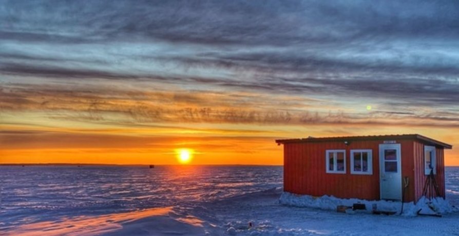 Ice hut on lake during sunset