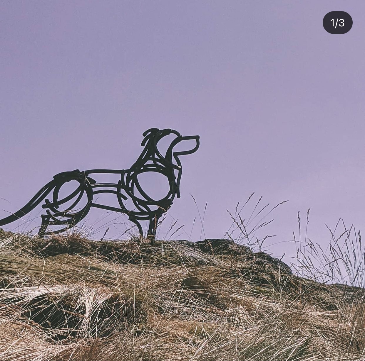 metal sculpture of a wolf situated on top of a mountain