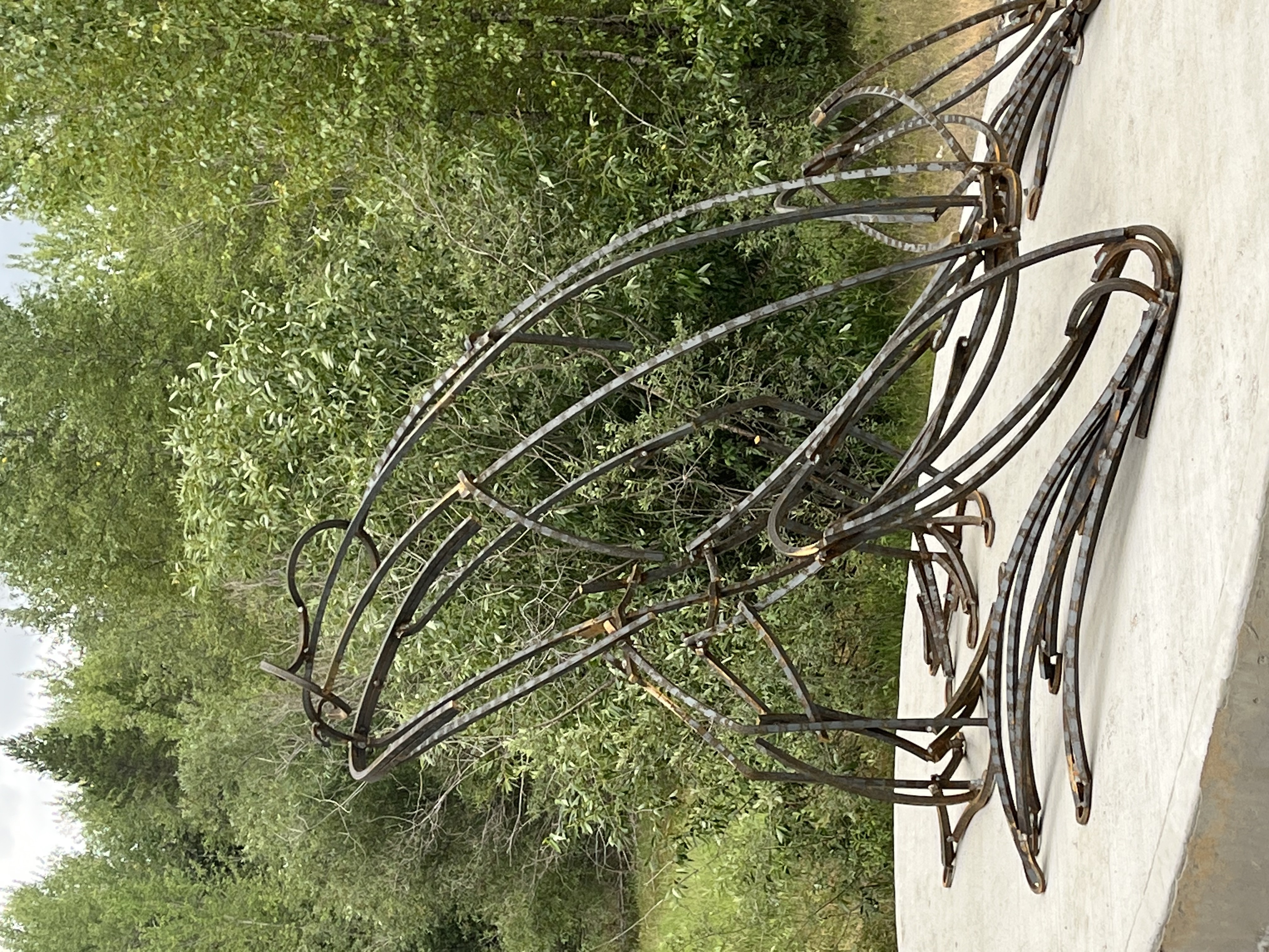 Metal sculpture of a toad with greenery in the background