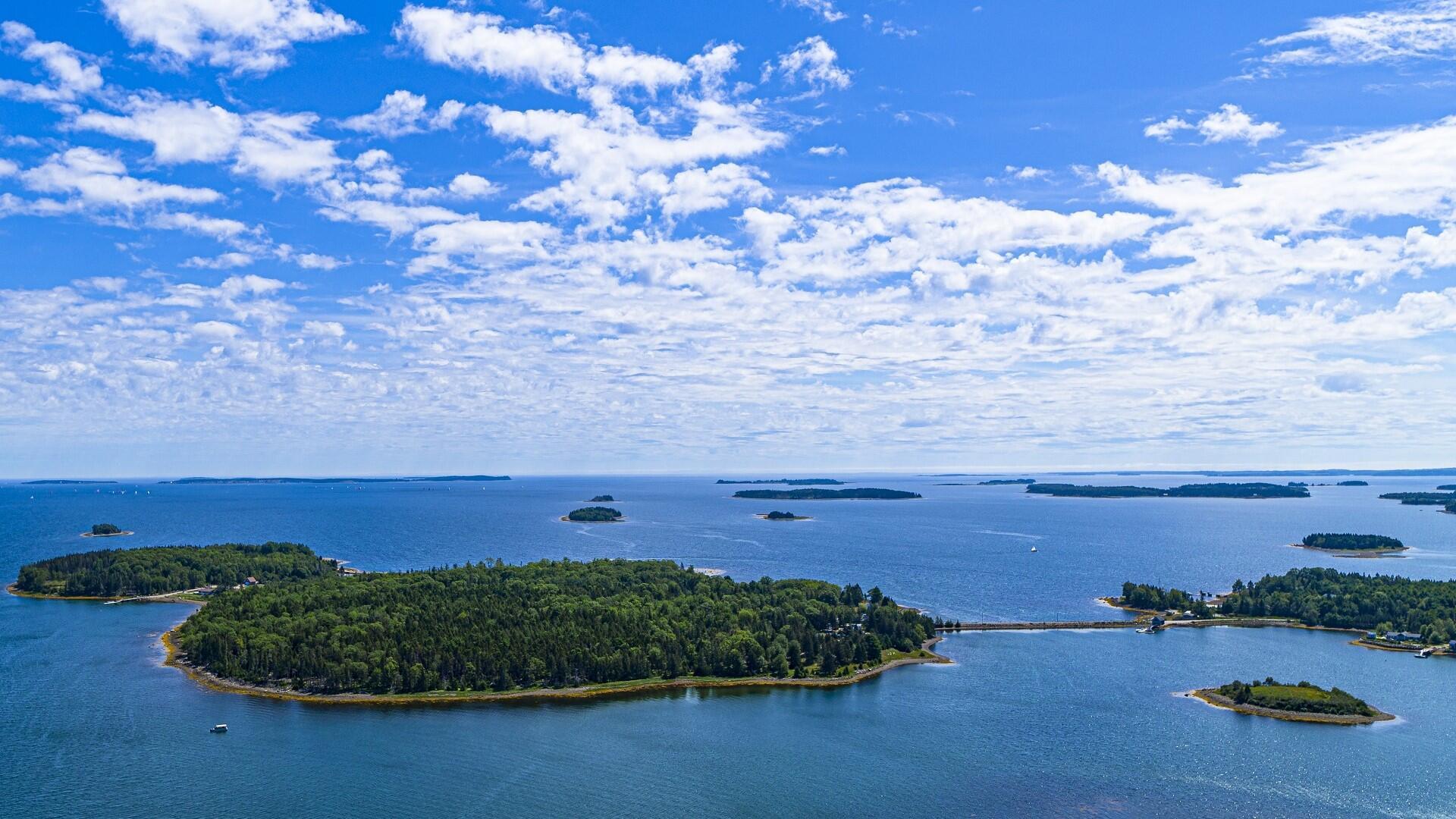 a bunch of islands in the water with the sky and clouds above it