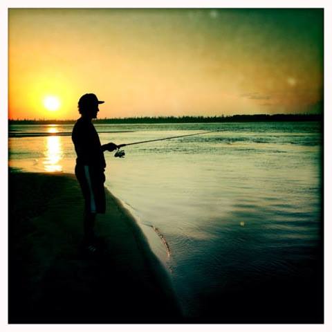 Person fishing on the water at sunset