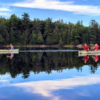 Two canoes on water with people