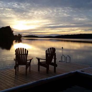 adirondack chairs on dock at sunset