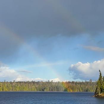 View of lake from shoreline with a rainbow