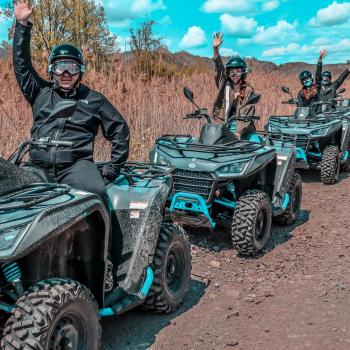 Multiple ATVs with people on them waving to the camera 