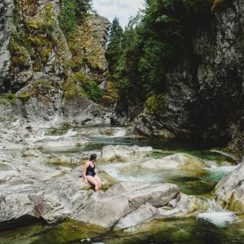 swimmer on rocks in river within a canyon