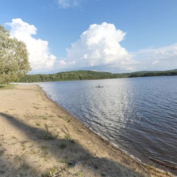 beach and calm lake on blue sky day