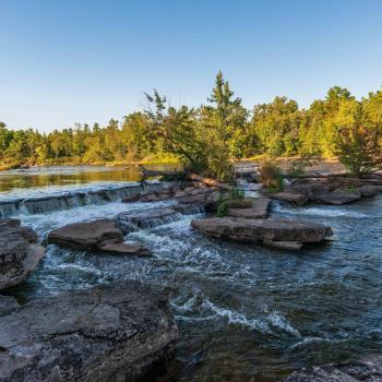 Water flowing around rocks with trees in the background