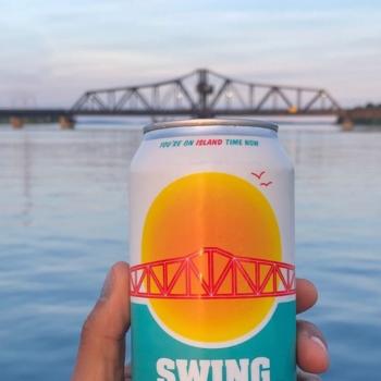 a can of beer with a lake and a bridge in the background