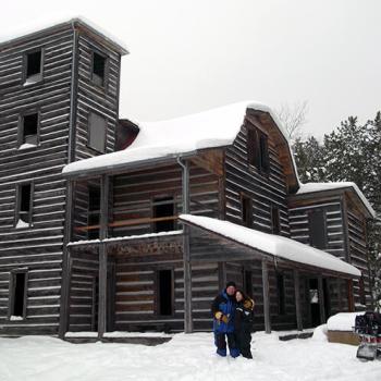 couple standing in front of abandoned wooden building in winter