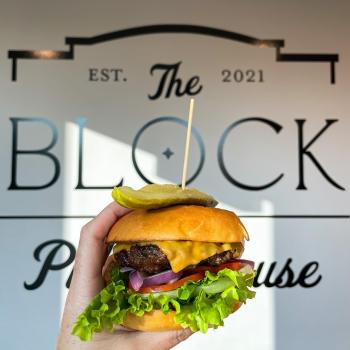 hamburger held up in front of The Block Public House sign