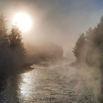 sun shining through mist over river