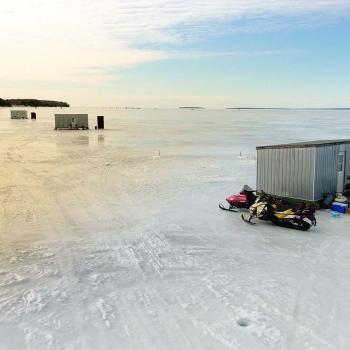 Ice huts on lake with snowmobiles