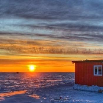 Ice hut on lake during sunset