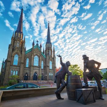 a statue with two men in front of a church